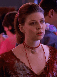a woman wearing a red choker necklace with a pendant on it