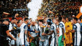 a group of soccer players are celebrating with a trophy and confetti