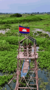 an aerial view of a wooden bridge over a river with a flag flying in the background .