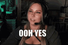 a woman wearing headphones says ooh yes in front of a computer
