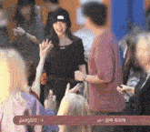a man in a red shirt is talking to a woman in a black top who is wearing a black hat
