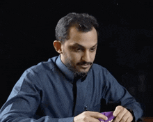 a man in a blue shirt is sitting at a table