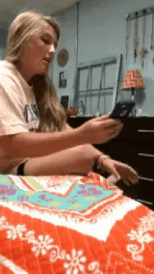 a woman is sitting on a bed looking at her cell phone