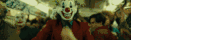 a man wearing a clown mask is walking through a crowd .