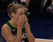 a woman wearing a minnesota jersey covers her face