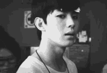 a black and white photo of a young man wearing a white shirt .