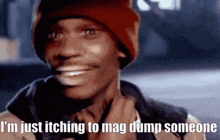 a man wearing a red beanie is smiling and saying i 'm just itching to mag dump someone
