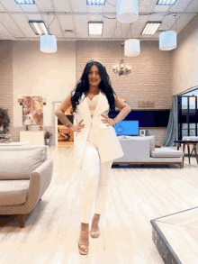 a woman in a white suit stands in a living room with a sign on the wall that says ' a '