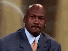 michael jordan is wearing a suit and tie while a small child holds his tie .