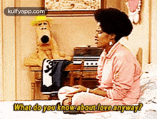 a woman is sitting on a bed talking to a stuffed animal and asking what do you know about love anyway .