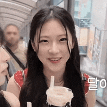 a girl with long hair is holding a cup with a straw in it and smiling