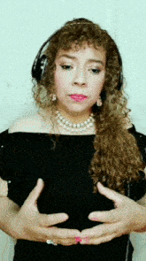 a woman with curly hair wearing headphones and pearls