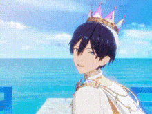a boy with a crown on his head is standing on a beach .