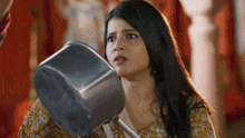 a woman is holding a pot in her hand and looking at it .