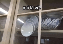a stack of plates and bowls in a glass cabinet with the words mo la vo written on the glass