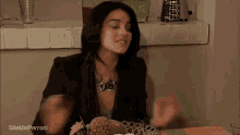 a woman is sitting at a table with a plate of food and the words sitemailperroni on the bottom right corner