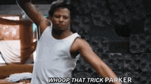a man in a white tank top is dancing in a room with his arms outstretched .