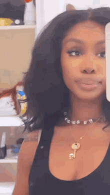 a woman is taking a picture of herself in a mirror . she is wearing a necklace with a key on it .