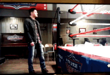a man stands in front of a wrestling ring with a sign that says " to bitch " on it