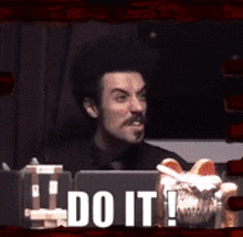 a man sitting in front of a laptop with the words " do it " written on it
