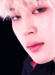 a close up of a person 's face with a pink lip and a black background .