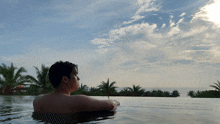 a man is swimming in an infinity pool with palm trees behind him