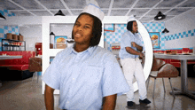 a man in a diner wearing a white hat and a blue and white striped shirt