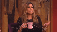 wendy williams is holding a pink mug with the name wendy on it