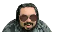 a man with a beard wearing sunglasses and headphones looks at the camera