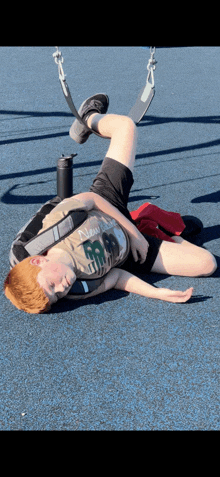 a young boy wearing a shirt that says new york lays on the ground