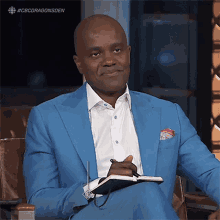 a man in a blue suit sits in a chair with a notebook in his lap