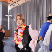 a man wearing a lei and holding a bouquet of flowers is standing in front of a woman playing a violin