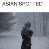 a person taking a picture in the snow with asian spotted written on the bottom