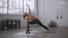 a woman is doing yoga on a mat with the word bustle on the bottom right