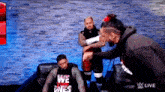 a group of men are sitting on a couch and one of them is holding another man 's hand .