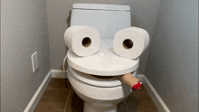 a toilet with a face made out of toilet paper and a cigarette sticking out of it