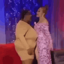 two women are standing next to each other on a red couch .