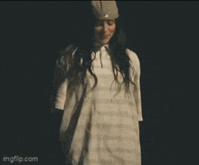 a woman in a white dress and hat is standing in a dark room