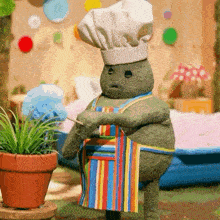 a stuffed animal wearing a chef 's hat and apron holds a toothpick