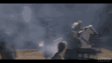 a man is riding on the back of a white horse in a smokey area .