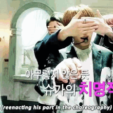 a man in a suit is covering his eyes with his hands and the words reenacting his part in the choreography are below him
