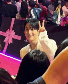 a man giving a peace sign in front of a gift box