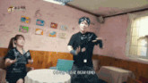 a man and a woman are dancing in a room with bgm in the corner