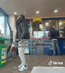 a man in a black jacket is standing in front of a counter with a sign that says ' send me money '