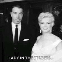 a black and white photo of a man and woman standing next to each other .