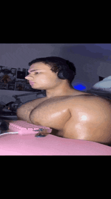 a man with huge muscles is wearing headphones and a pink keyboard