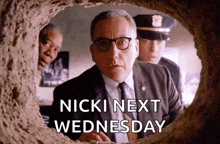 a man in a suit and tie is looking through a hole with the words nicki next wednesday below him