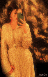 a woman in a white dress is taking a selfie with her cell phone