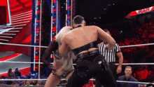 two women are wrestling in a wrestling ring with a referee watching .