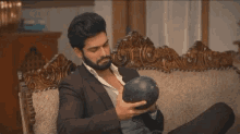 a man in a suit is sitting on a couch holding a black object